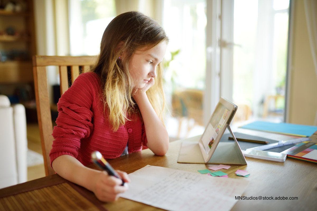 child doing schoolwork at home with a tablet