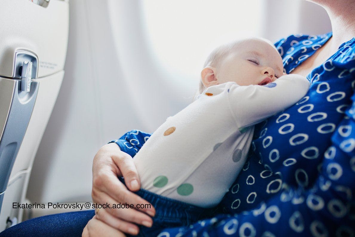 image of infant sitting on mother's lap on an airplane