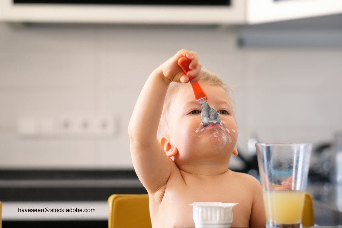 baby eating baby food with a spoon