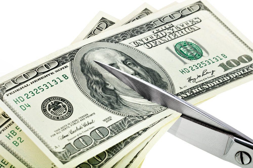 stock image of money being cut by scissors